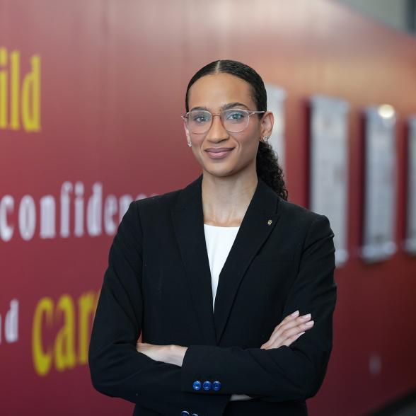 Graduate student posing with arms crossed smiling at camera