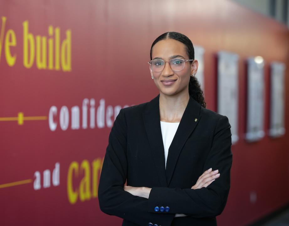 Female student in black suit stands near the Career Services office