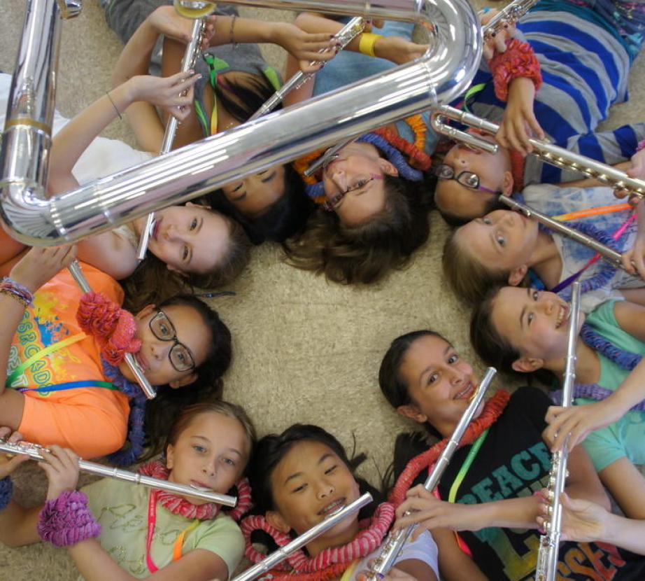 Circle of children playing flutes looking up 